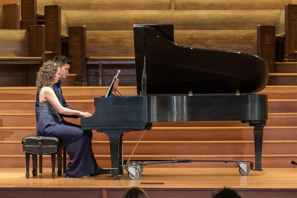 Image of pianists Sarah Gibson and Thomas Kotcheff playing a piano together on stage