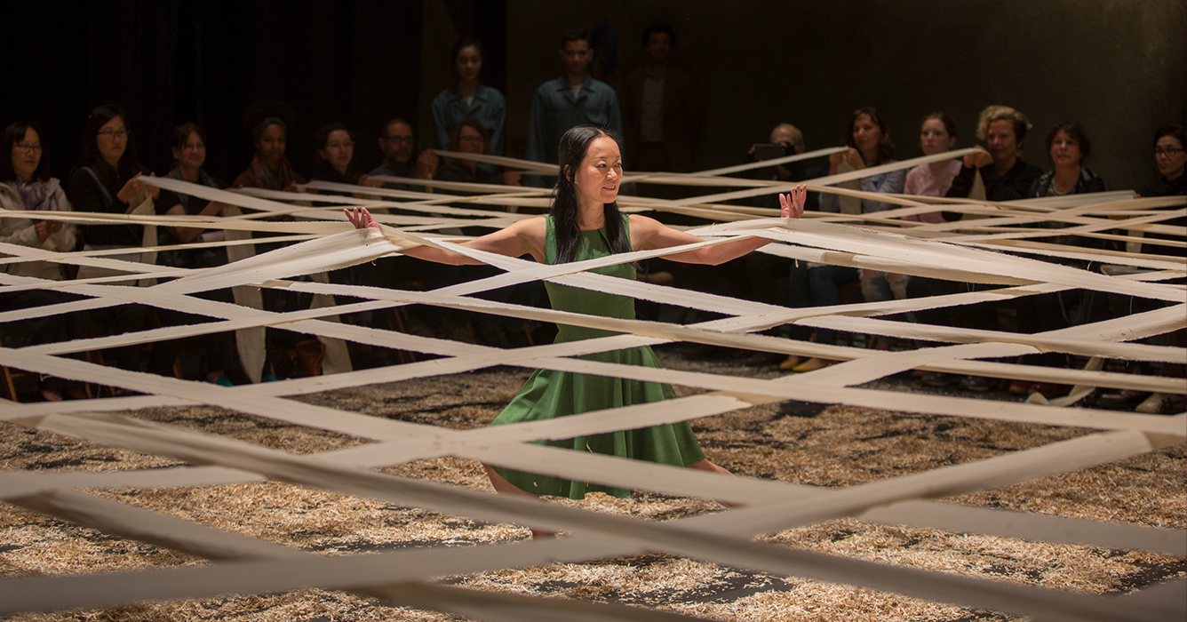 Woman dancing among paper surrounded by audience