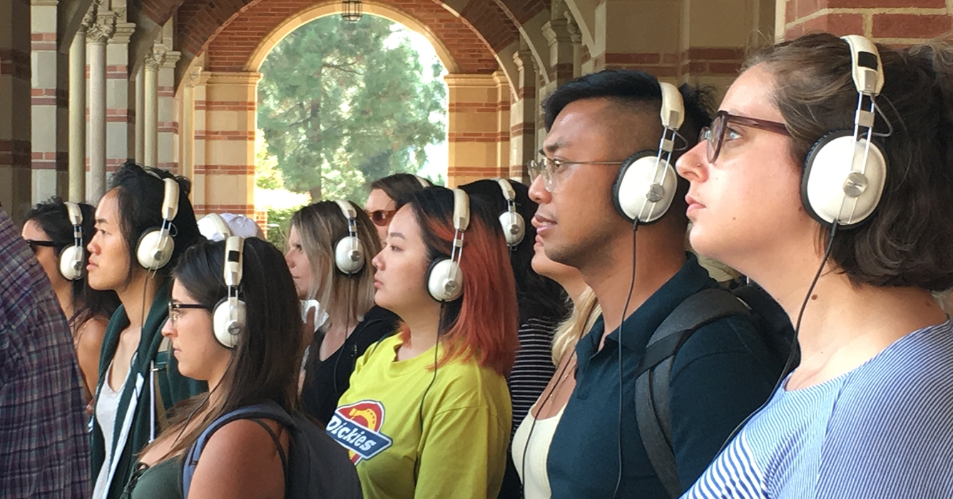 Group of people under Royce Hall arches with headphones on