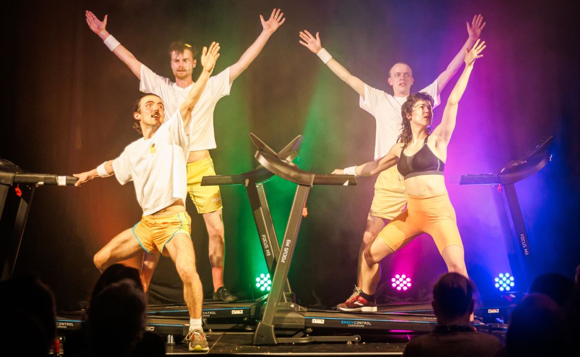 Pony Cam Collective performs on stage on 4 treadmills and rainbow lighting