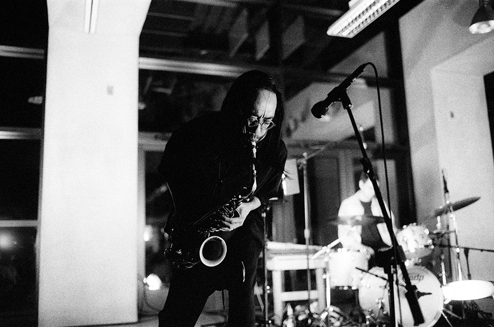 Wild Up lead artist for 2027 show Patrick Shiroishi in black and white photo playing saxophone 