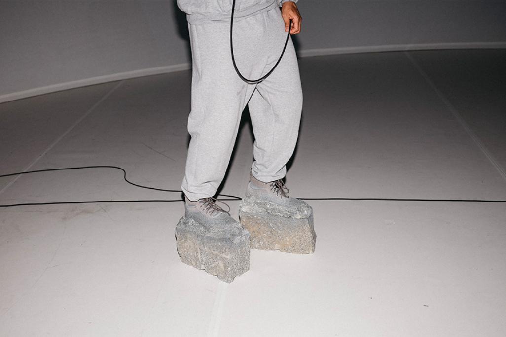 Image of pair of legs wearing grey sweat pants and shoes and made of concrete