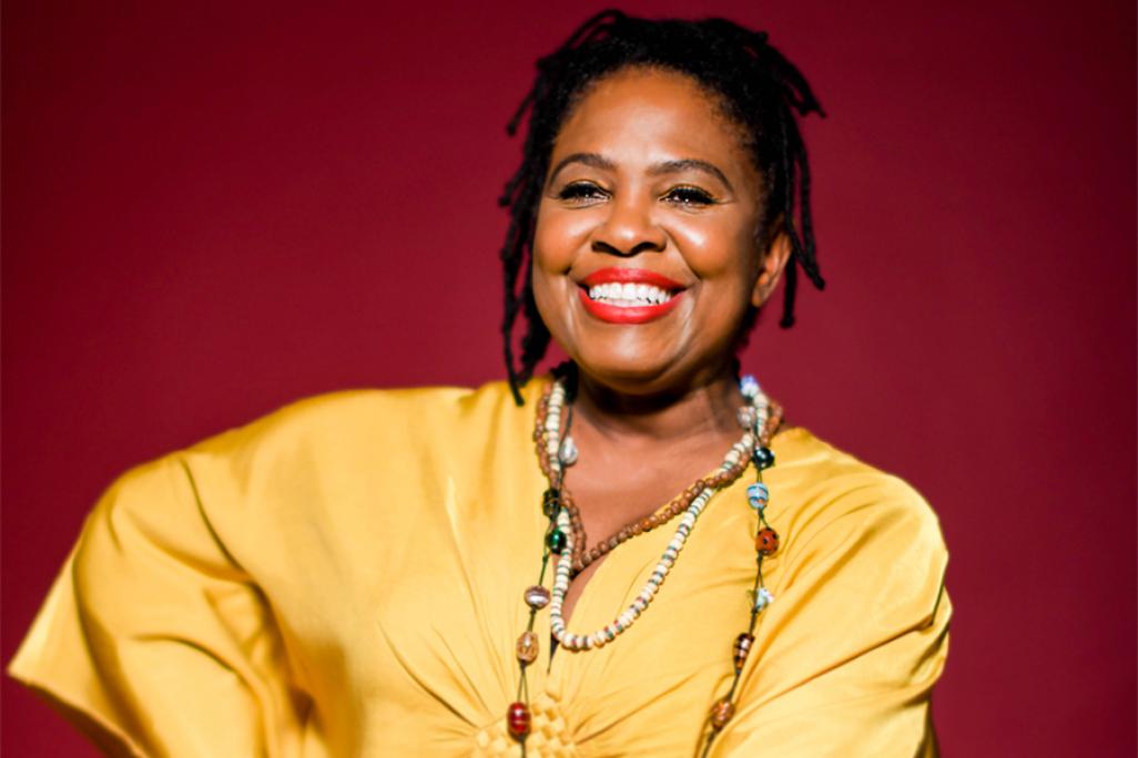 Ruthie Foster smiles in front of a red background