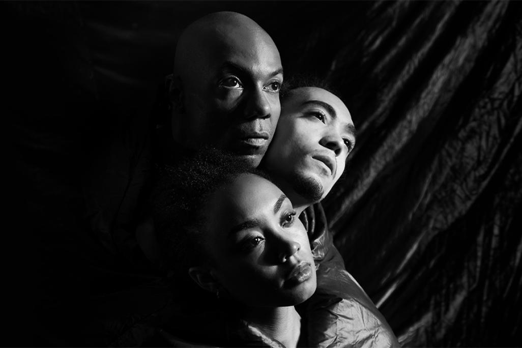 Shamel Pitts poses with two dancers in black and white lighting in a close up photo