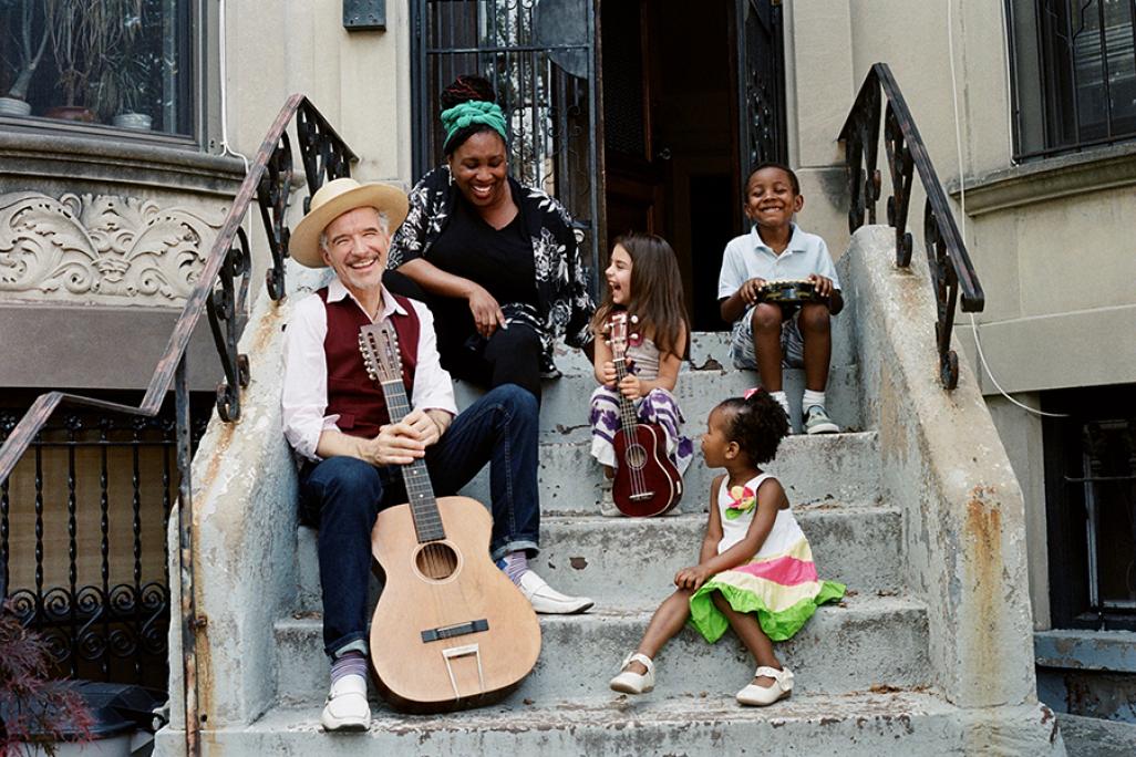 Dan  & Claudia Zanes playing music on the steps of a neighborhood with kids