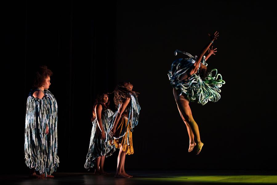 four dancers on stage in cultural dress with a black backdrop