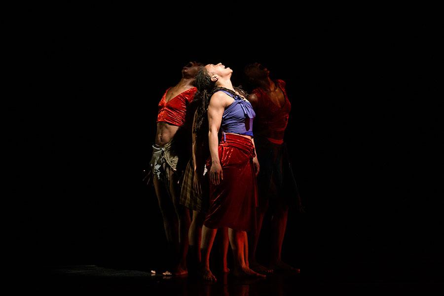 Three dancers with their backs turned to each other mid performance