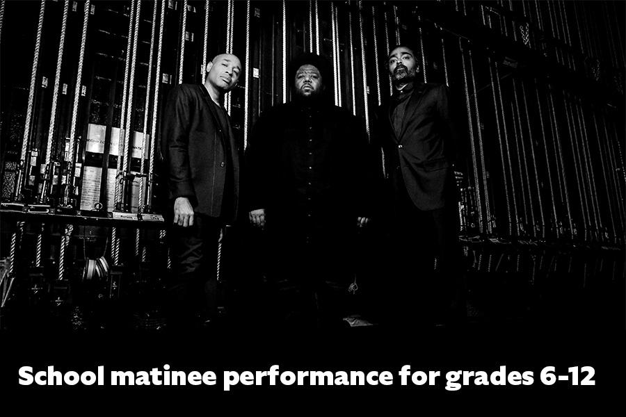Black and white photo of Tyshawn Sorey Trio posing backstage with text reading School Matinee Performance Grades 6-12 superimposed at bottom