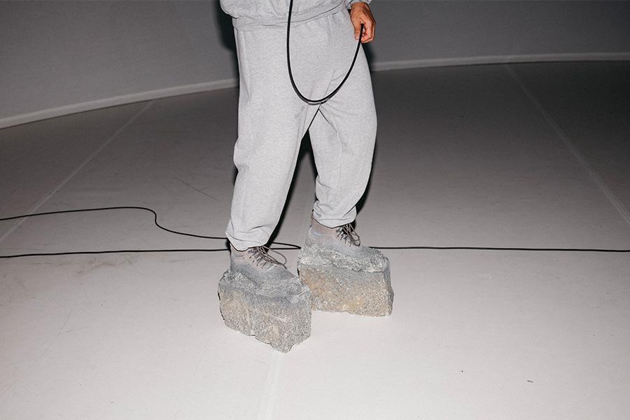 Image of pair of legs wearing grey sweat pants and shoes and made of concrete