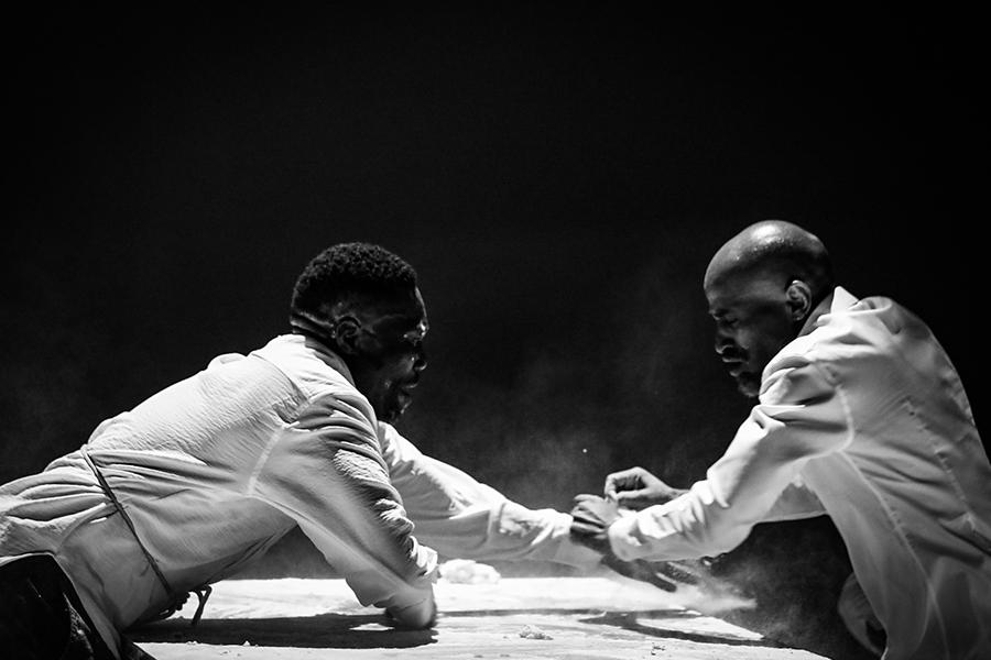 Black and white image of two performers leaning towards each other