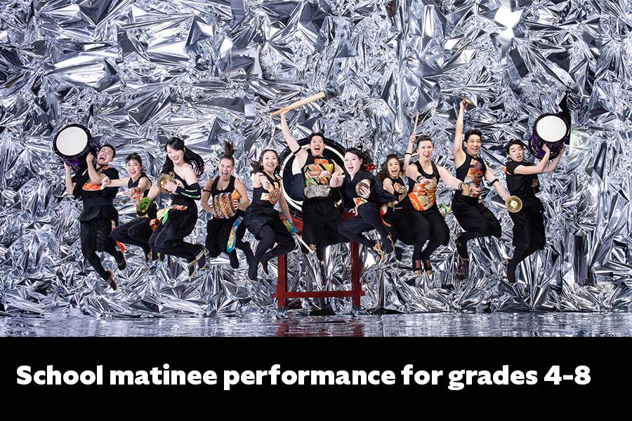 Members of TAIKOPROJECT posing for group shot with hand held instruments jumping in the air