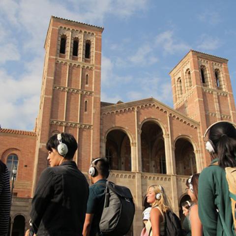 Group with head phones on in front of Royce Hall