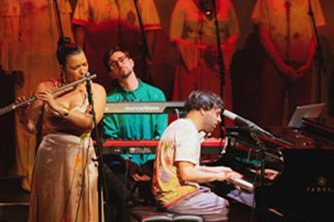 Samora Pinderhughes plays on stage with orange backdrop