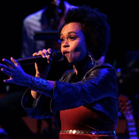 Meklit Hadero singing into a microphone on stage in size 1080x1080
