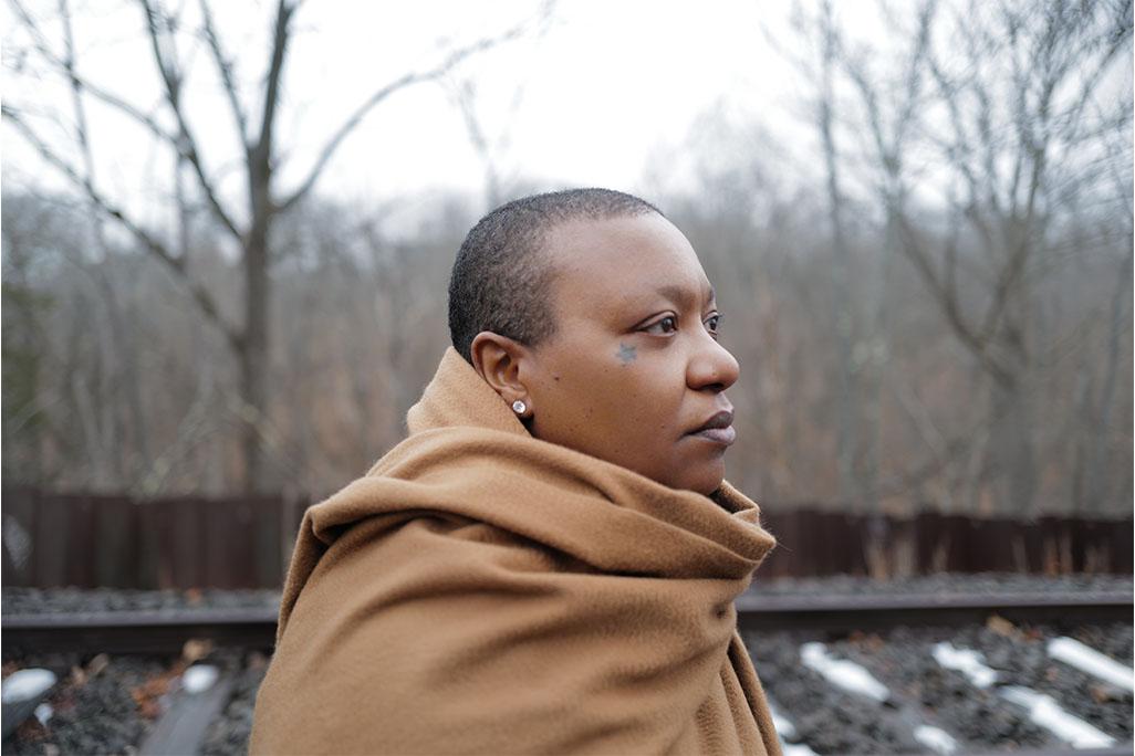 Close up photo of Meshell Ndegeocello standing in woods looking to the right