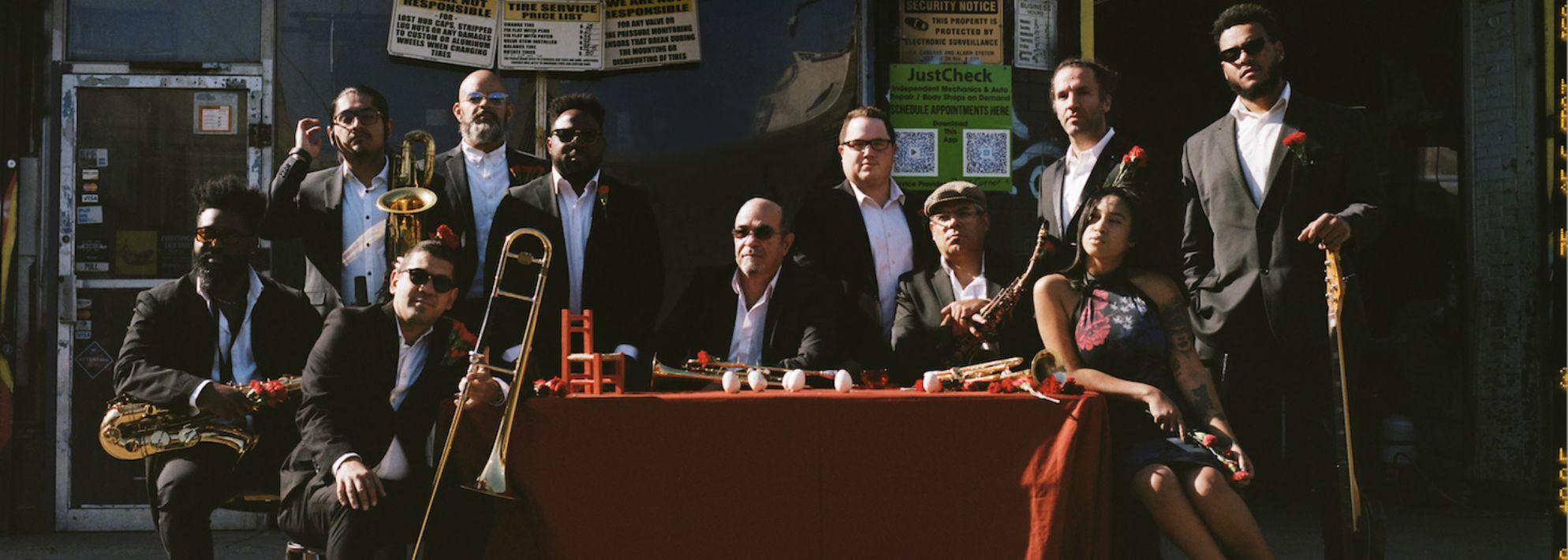 ORQUESTA AKONAN POSES OUTDOORS AROUND A TABLE