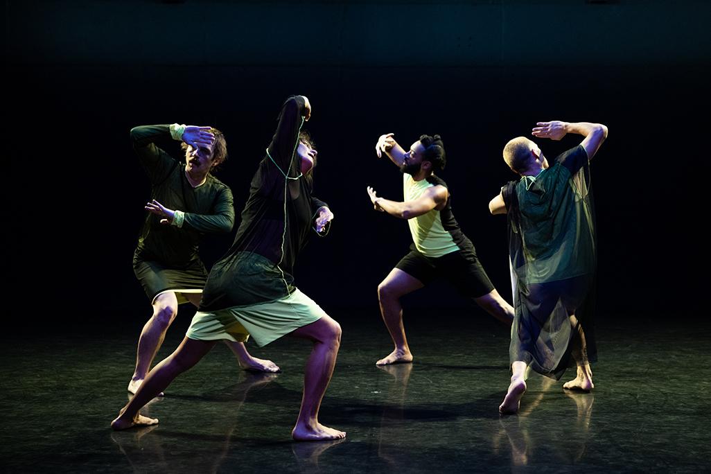 Dancers perform in front of a black backdrop