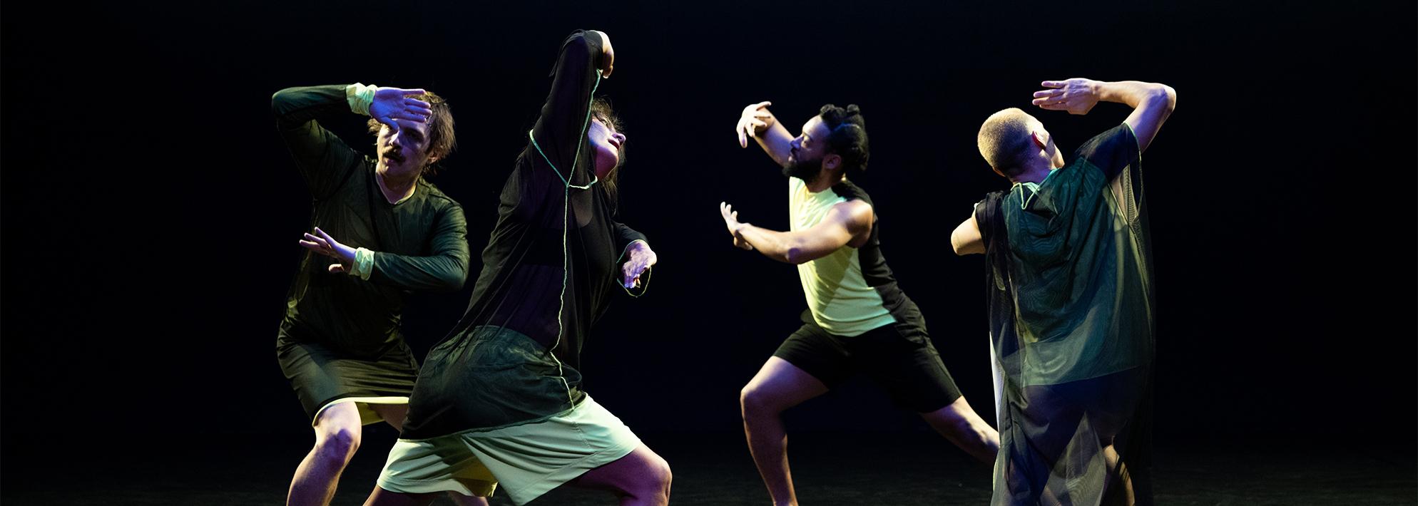 Dancers perform in front of a black backdrop