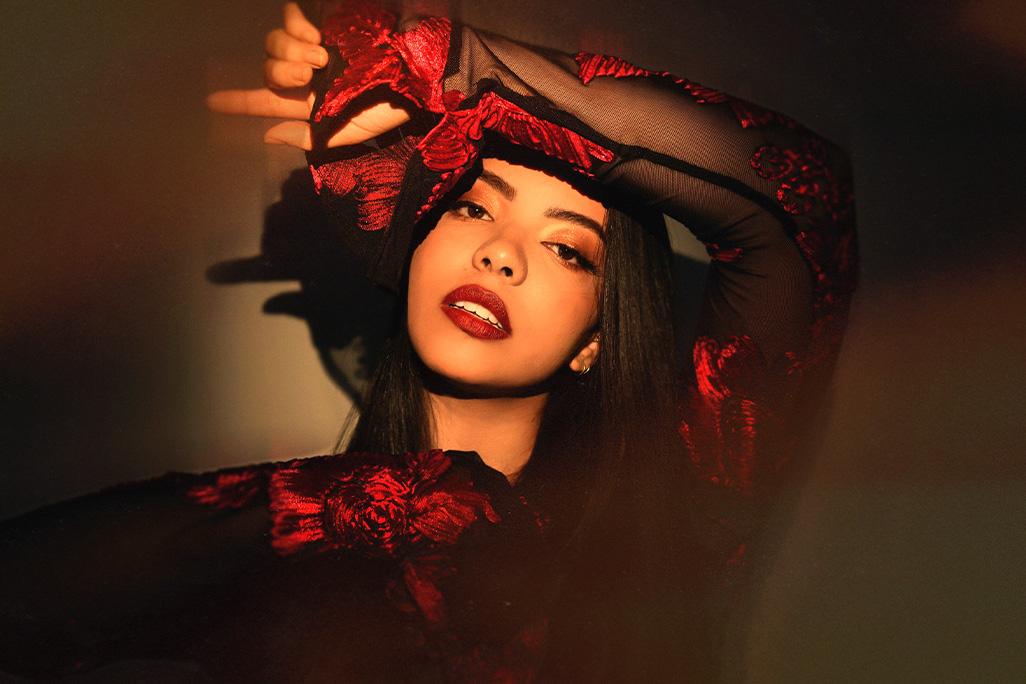 Photo of Lucía posed in a spotlight with a solid colored backdrop behind her