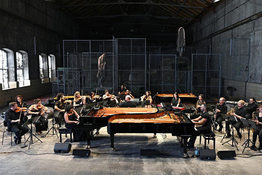 Members of the Wild Up ensemble play their instruments in large warehouse room