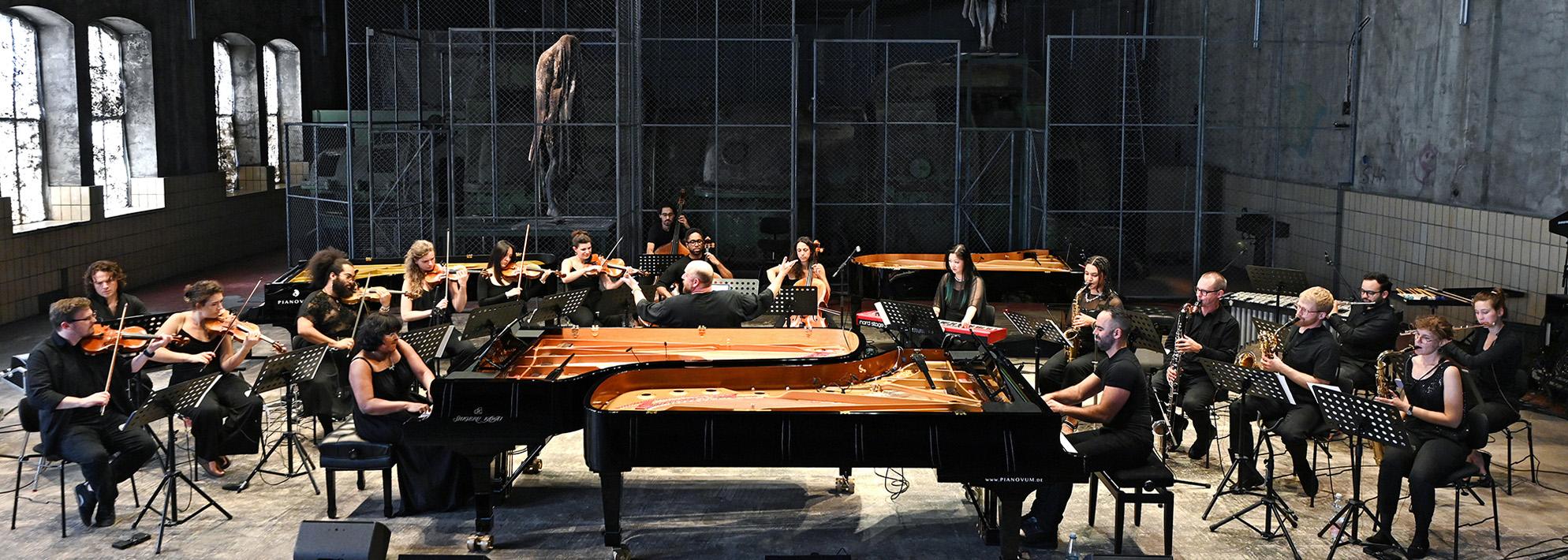Members of the Wild Up ensemble play their instruments in large warehouse room