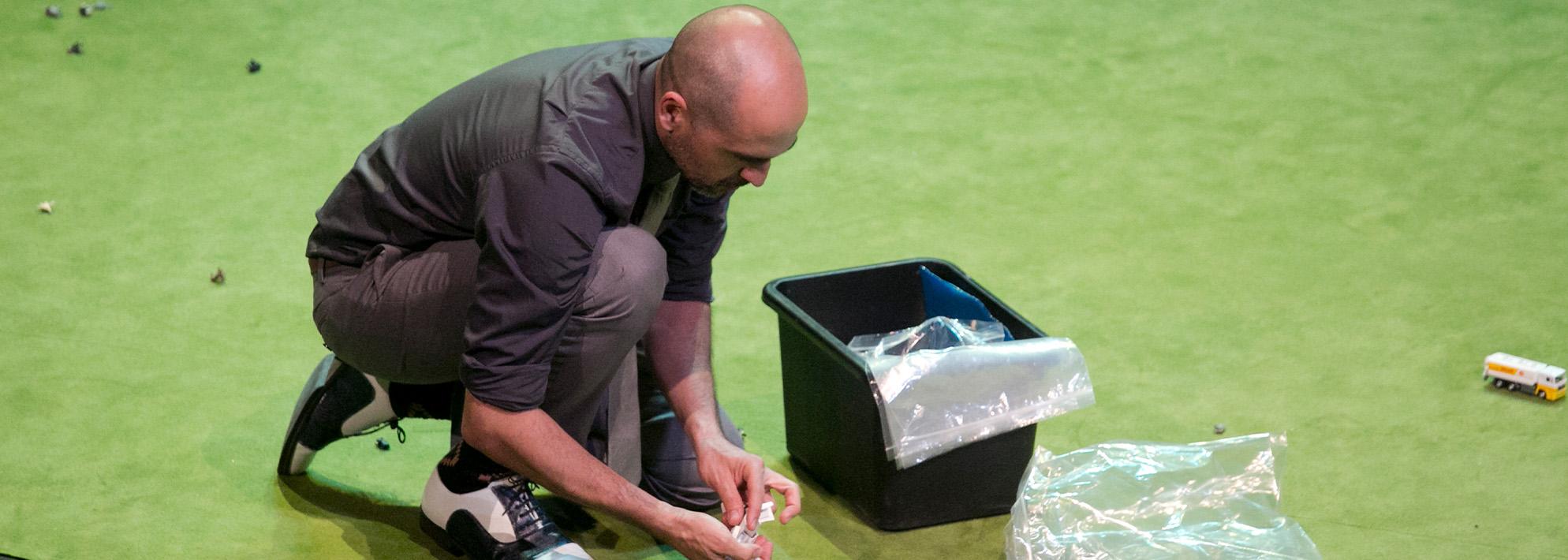 A performer crouches on stage and adjusts miniatures 