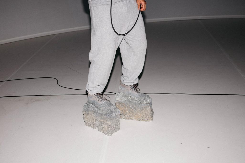 Cropped image of two legs wearing shoes with concrete base
