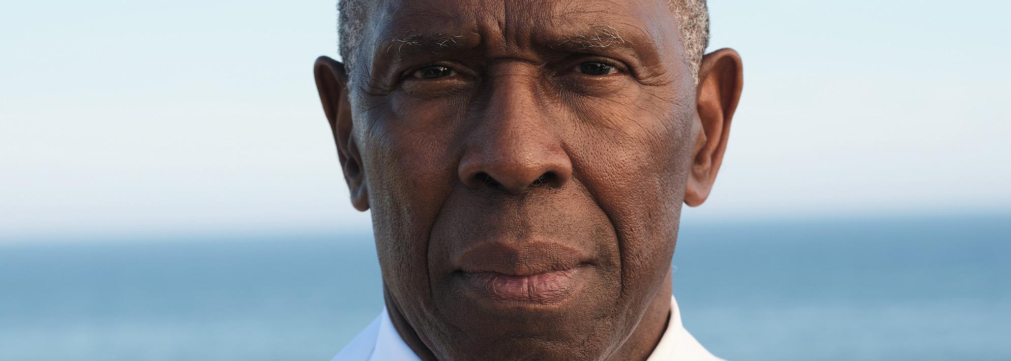 Headshot of Charles Gaines posing in front of an ocean backdrop