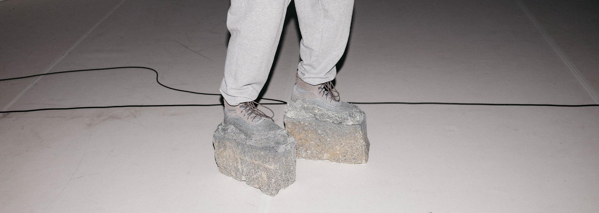 Cropped image of two legs wearing shoes with concrete base