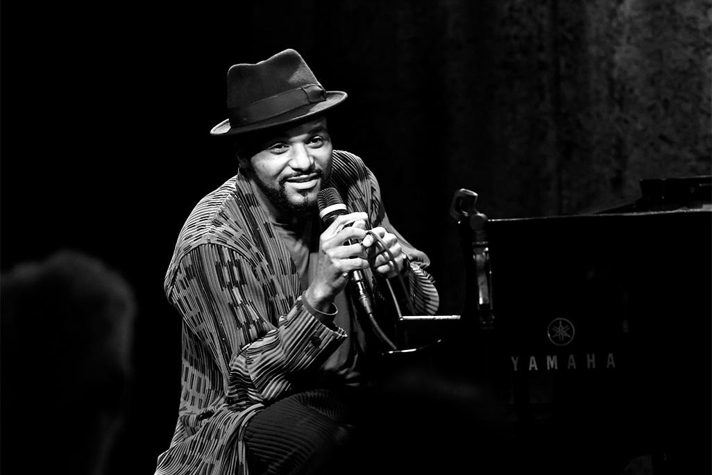 Black and white image of Sullivan Fortner speaking into a microphone