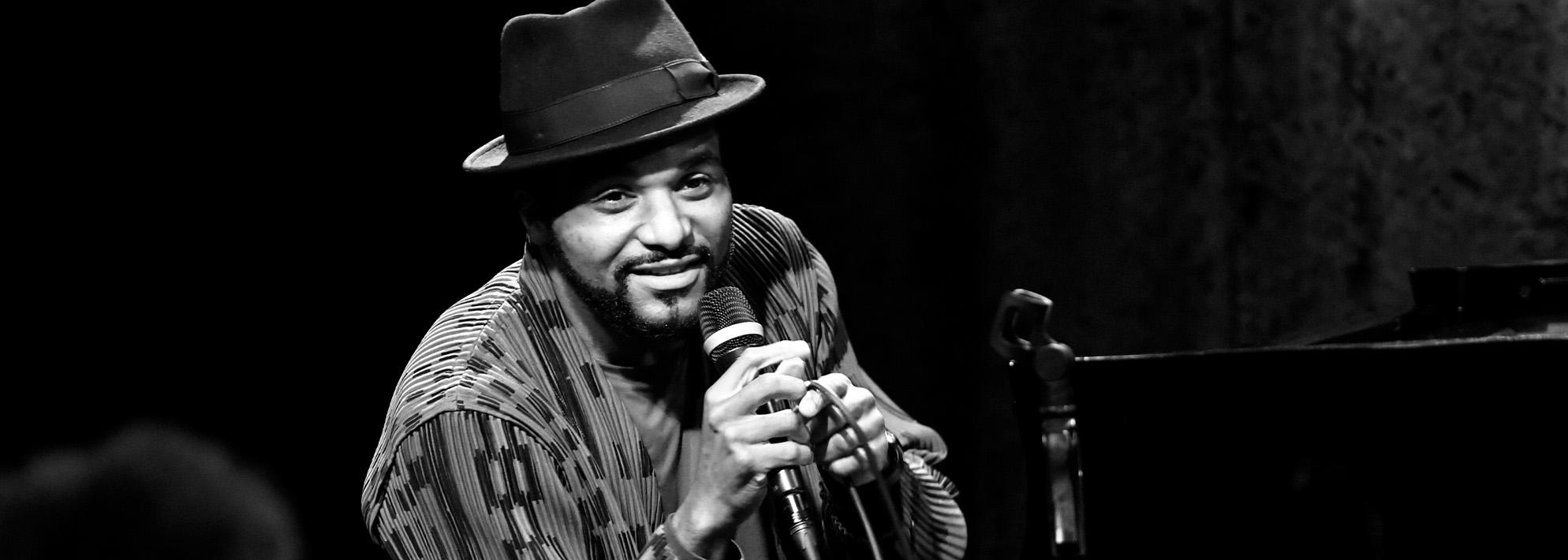 Black and white image of Sullivan Fortner speaking into a microphone