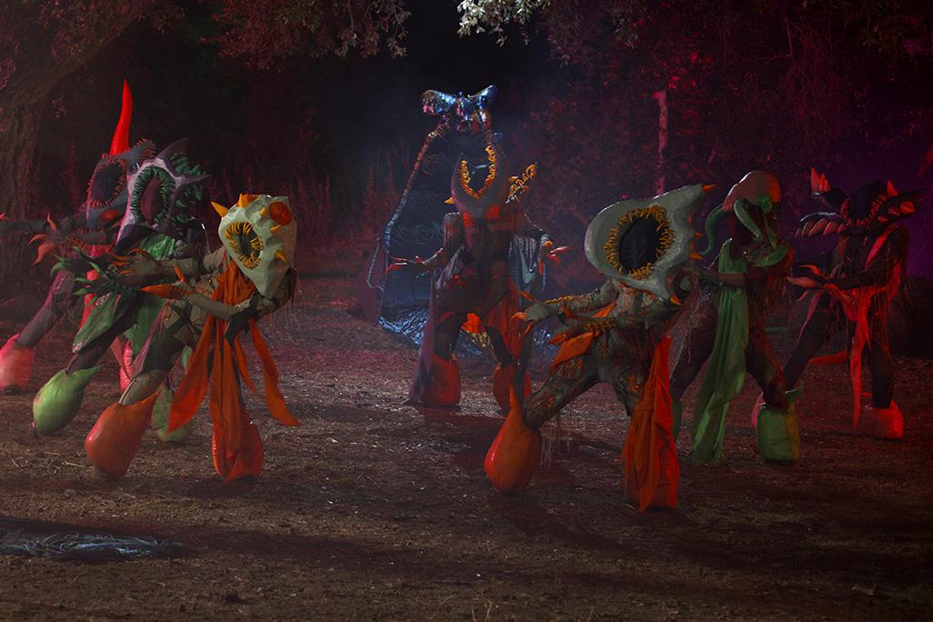 Still from 'Red All Night' featuring psychedelically colorful monster creatures dance in a forest at night