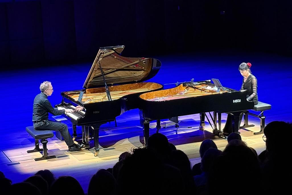 Ralph van Raat and Gloria Cheng perform on stage, seated at their respective pianos which are facing each other