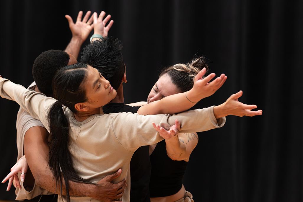 Image of dancers from 'A Deer Walks into a Dance' huddled together with their arms out stretched