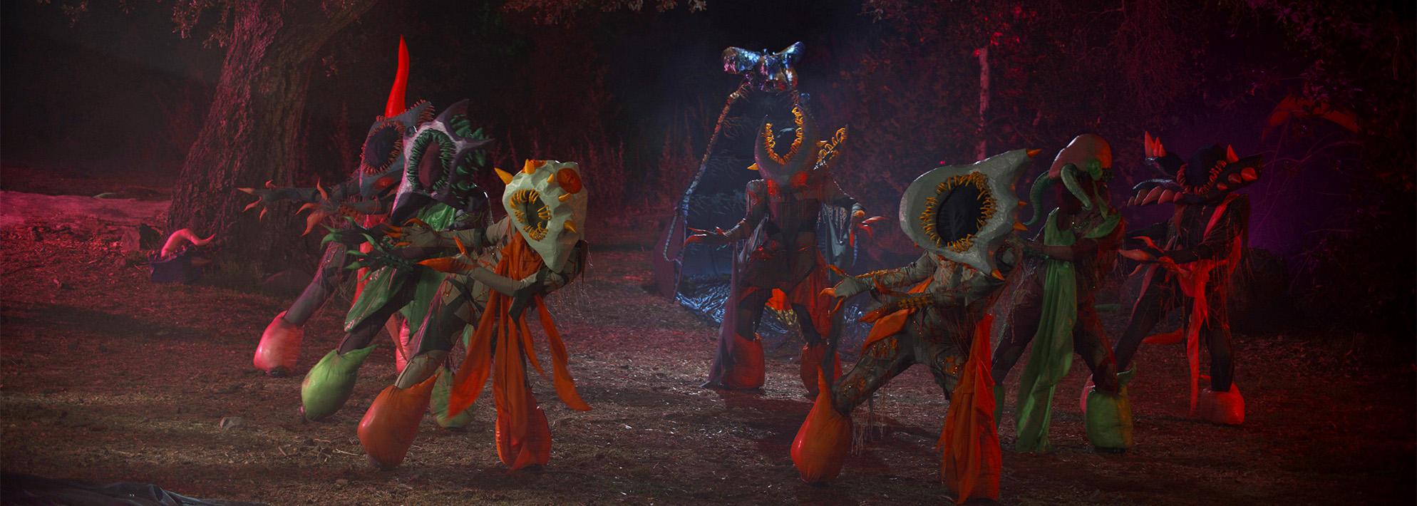 Still from 'Red All Night' featuring psychedelically colorful monster creatures dance in a forest at night
