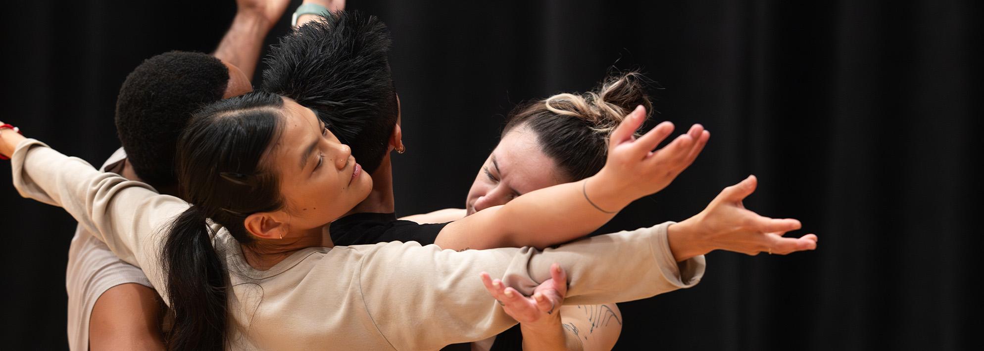 Image of dancers from 'A Deer Walks into a Dance' huddled together with their arms out stretched